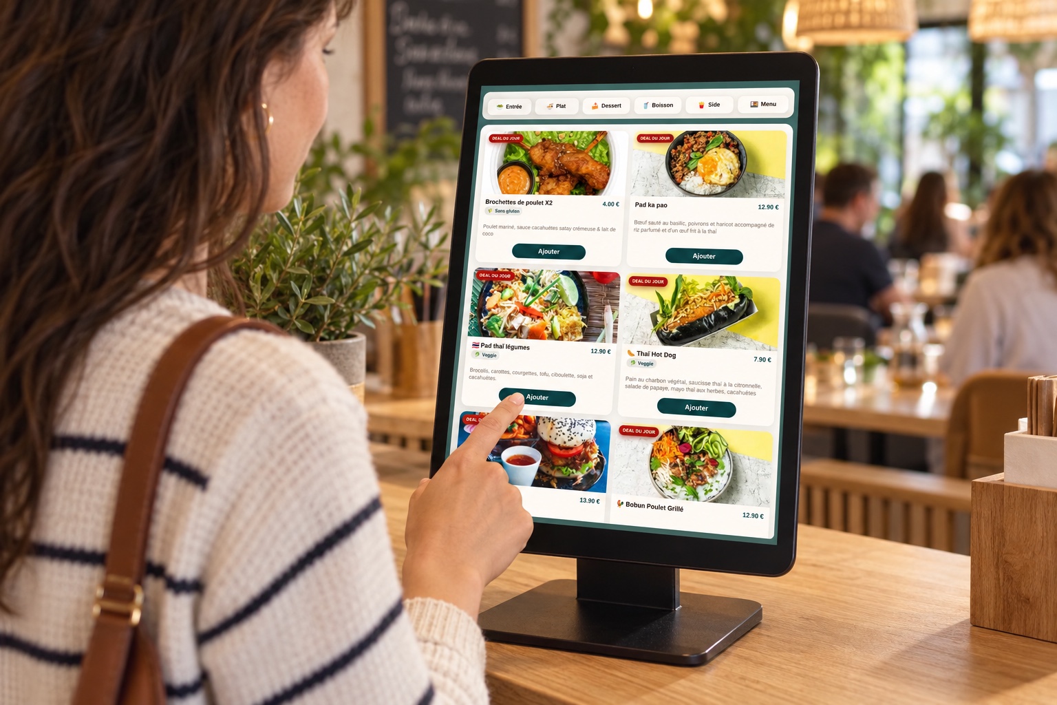 Une cliente choisit un plat sur la borne BEBORNE au comptoir d’un restaurant, avec l’interface réelle de commande
